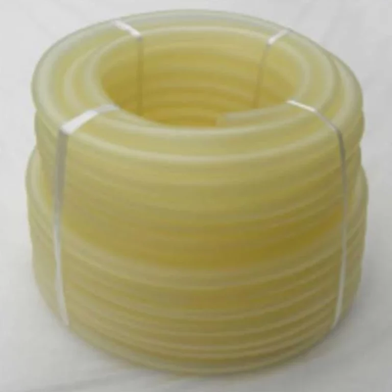 Rolled yellow plastic tubing coiled into a large coil, secured with white ties on a white surface