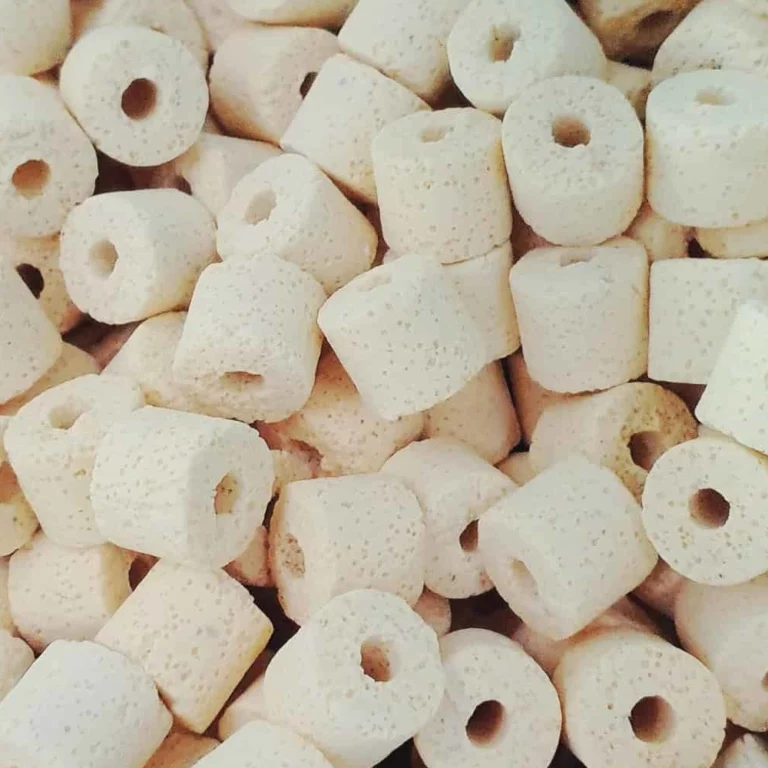 Pile of small white ring-shaped cereal pieces with a hole in the center, piled together.
